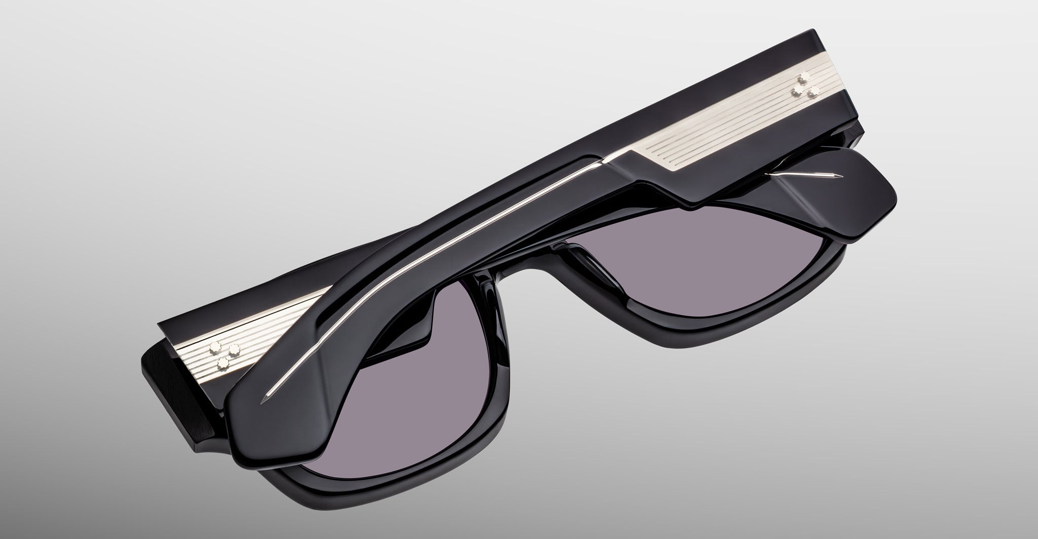 Jacques Marie Mage Dino in Bloodstone black acetate sunglass frame with grey lenses, gold arrowhead pins, and sculptural wide temples, angled back view highlighting layered temple construction and wirecore detail