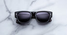 Jacques Marie Mage Dino in Bloodstone black acetate sunglass frame with grey lenses, gold arrowhead pins, and sculptural wide temples, front view