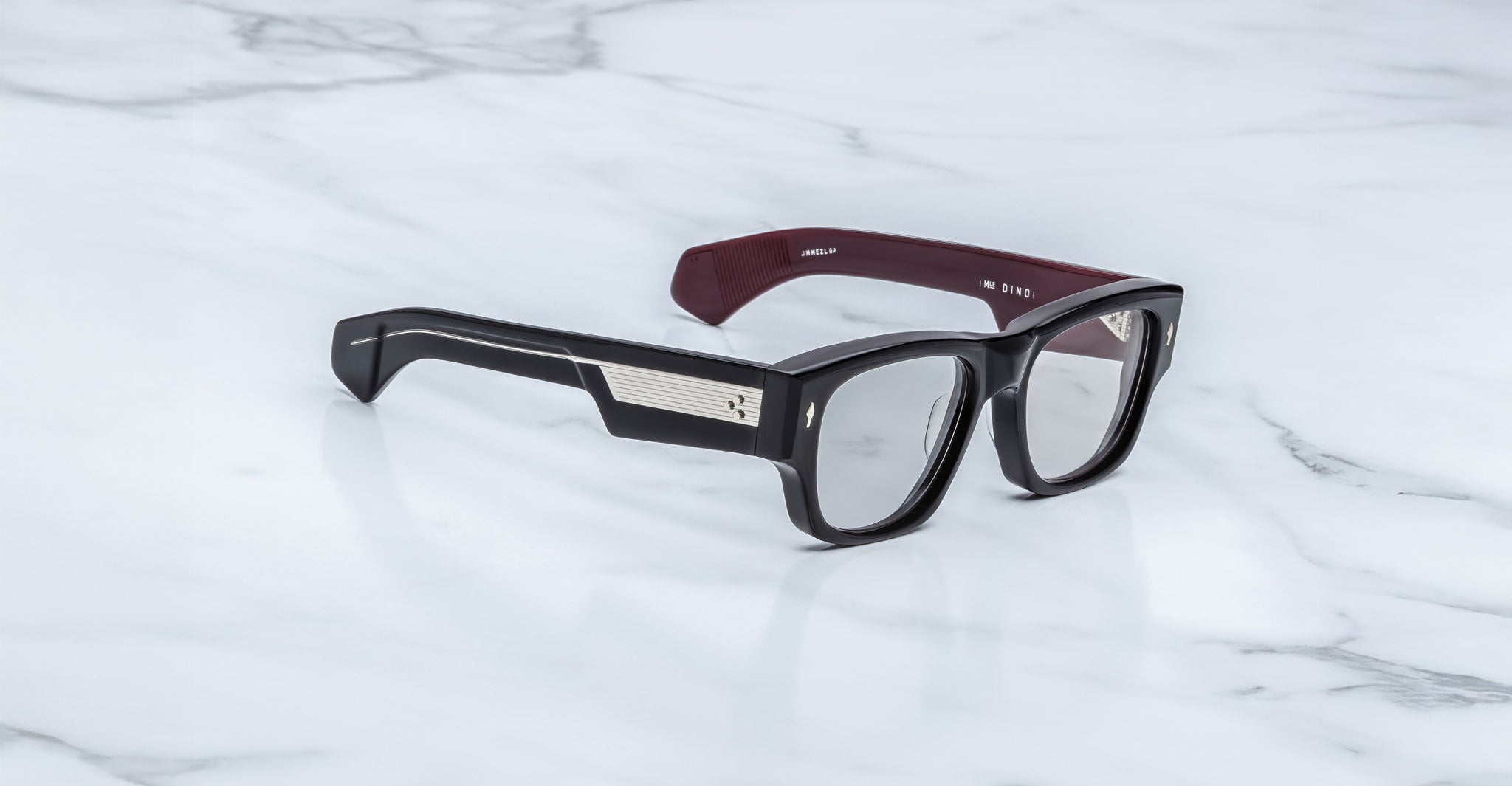 Jacques Marie Mage Dino in Bloodstone black acetate optical frame with clear lenses, gold arrowhead pins, and sculptural wide temples, three-quarter view showing front and temple profile