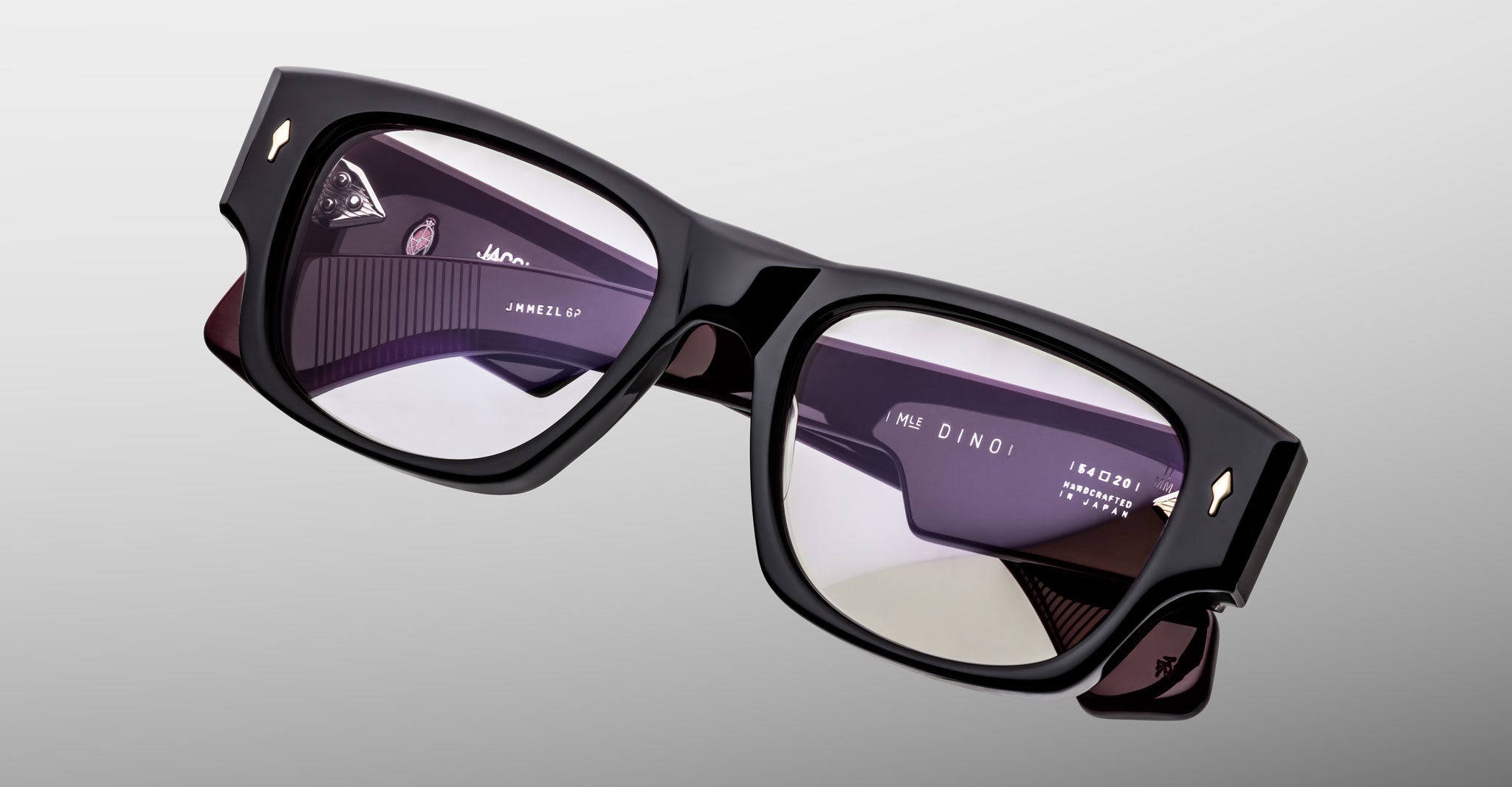 Jacques Marie Mage Dino in Bloodstone black acetate optical frame with clear lenses, gold arrowhead pins, and sculptural wide temples, angled top view showing lens and bridge detail