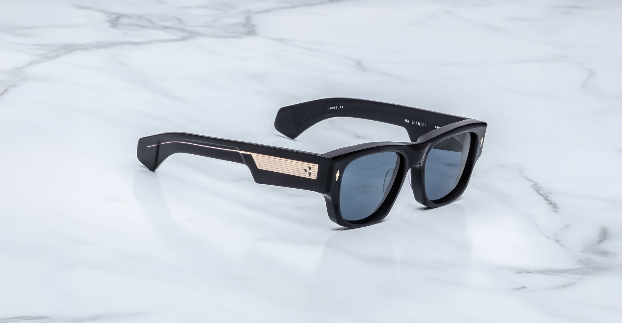 Jacques Marie Mage Dino in Lacquer dark blue acetate sunglass frame with lacquer dark blue lenses, gold arrowhead pins, and sculptural wide temples, three-quarter view showing front and temple profile