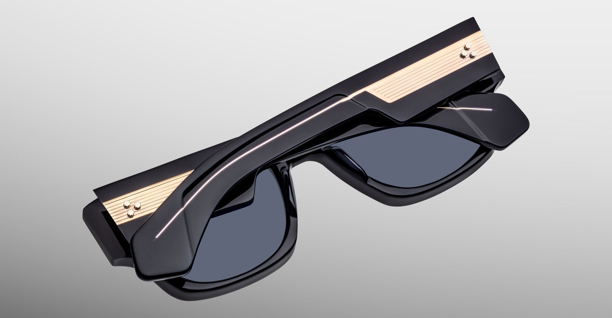 Jacques Marie Mage Dino in Lacquer dark blue acetate sunglass frame with lacquer dark blue lenses, gold arrowhead pins, and sculptural wide temples, angled view highlighting layered temple construction and wirecore detail