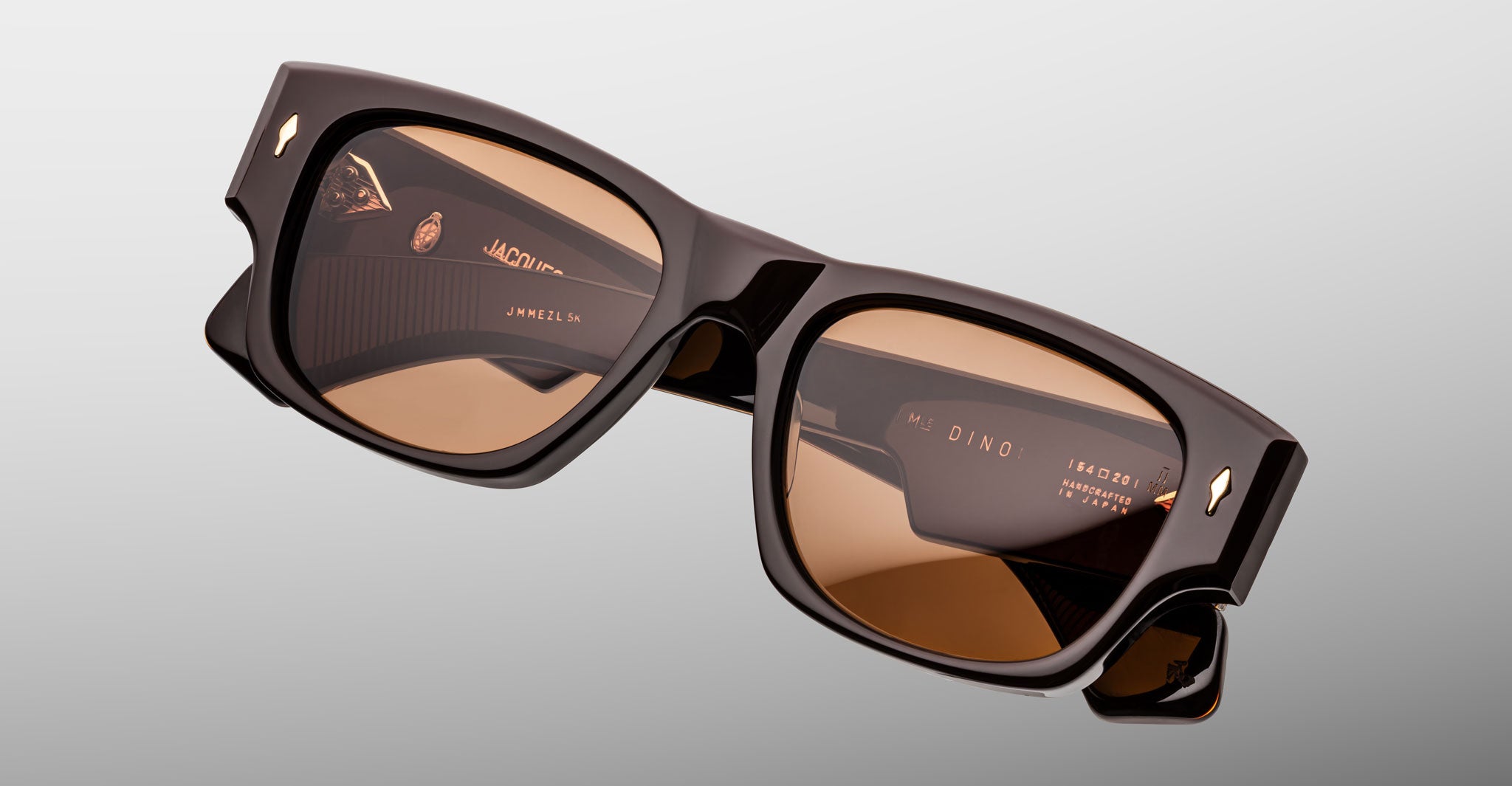 Jacques Marie Mage Dino in Walnut brown acetate sunglass frame with brown lenses, gold arrowhead pins, and sculptural wide temples, angled top view showing lens and bridge detail