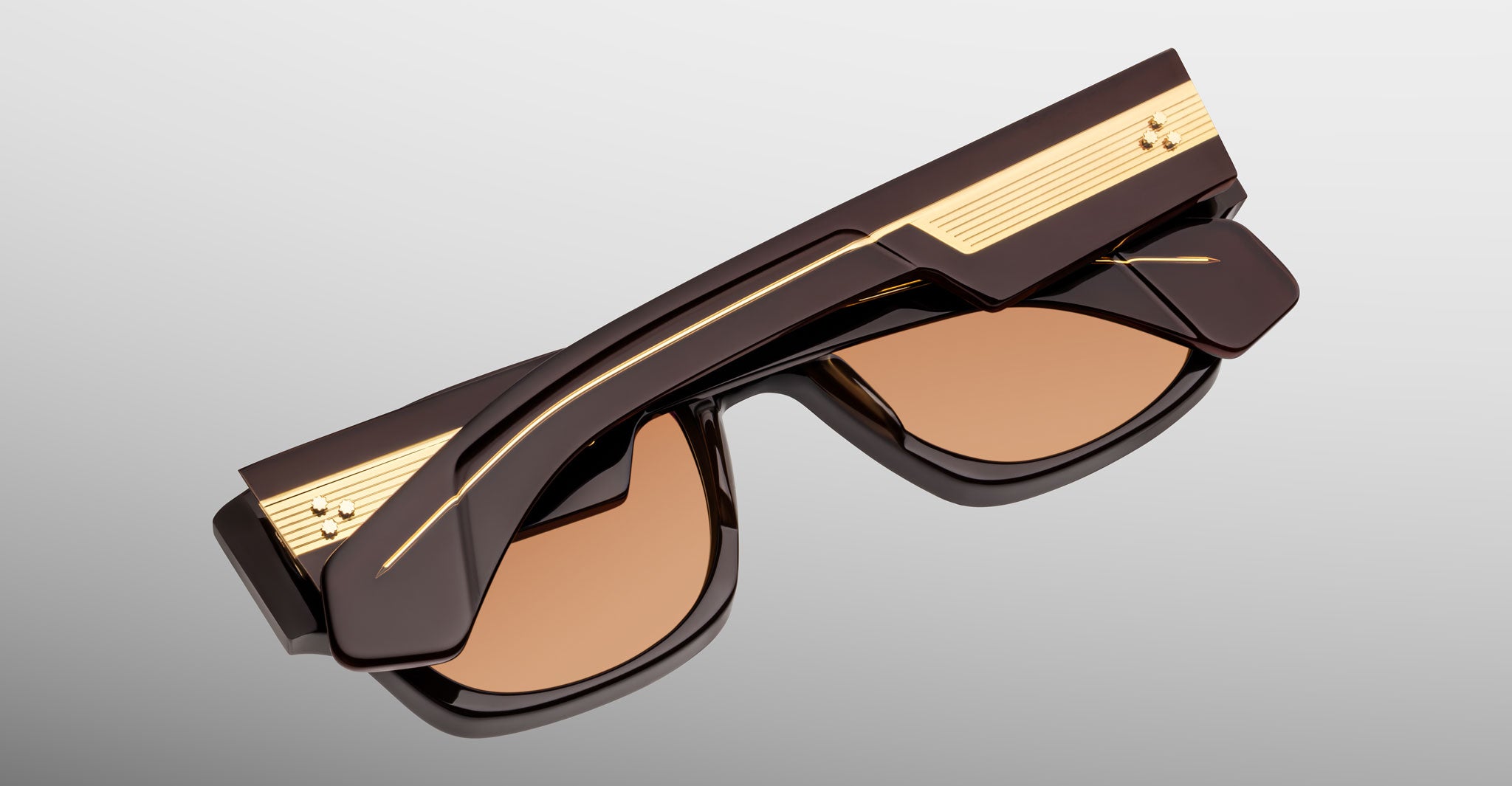 Jacques Marie Mage Dino in Walnut brown acetate sunglass frame with brown lenses, gold arrowhead pins, and sculptural wide temples, angled view highlighting layered temple construction and wirecore detail
