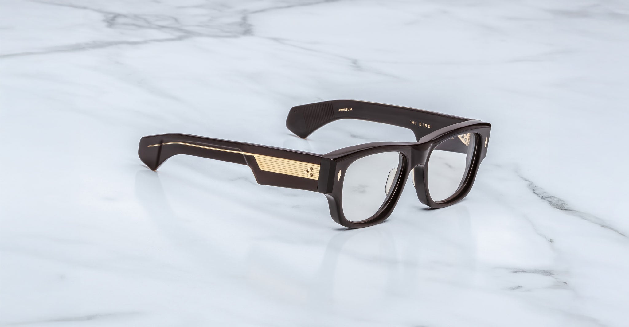 Jacques Marie Mage Dino in Walnut brown acetate optical frame with clear lenses, gold arrowhead pins, and sculptural wide temples, three-quarter view showing front and temple profile
