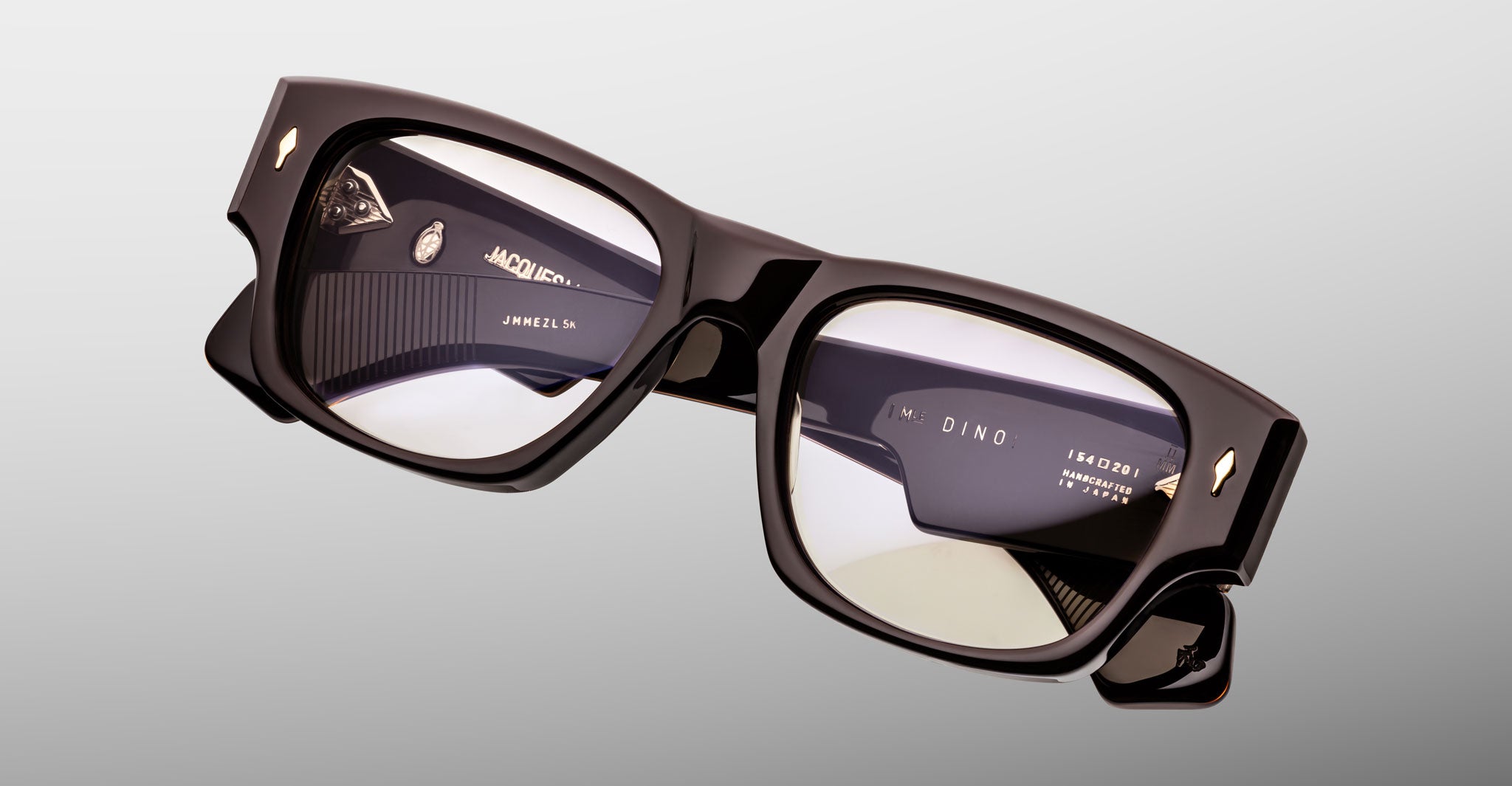 Jacques Marie Mage Dino in Walnut brown acetate optical frame with clear lenses, gold arrowhead pins, and sculptural wide temples, angled top view showing lens and bridge detail