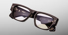 Jacques Marie Mage Dino in Walnut brown acetate optical frame with clear lenses, gold arrowhead pins, and sculptural wide temples, angled top view showing lens and bridge detail