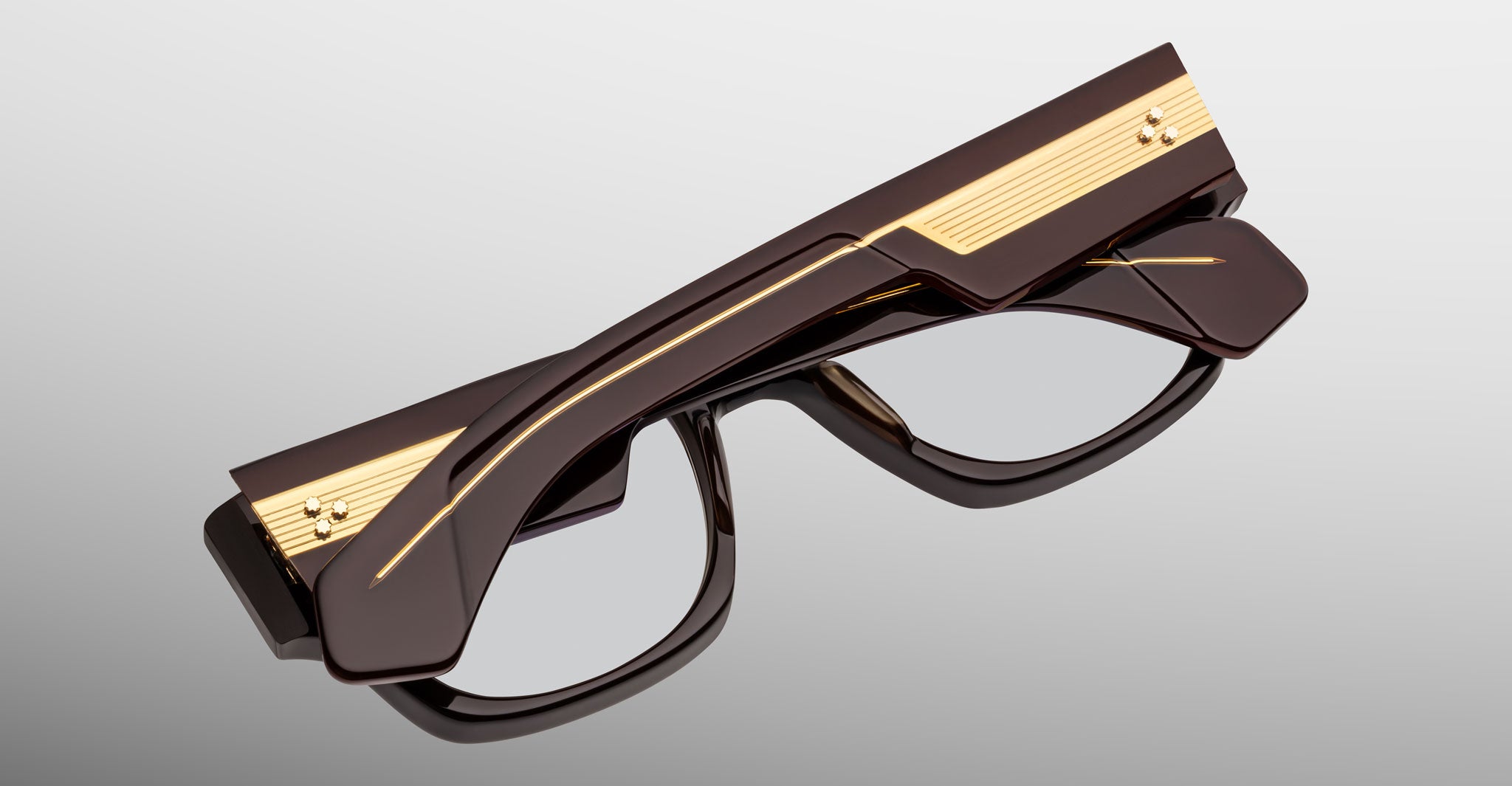 Jacques Marie Mage Dino in Walnut brown acetate optical frame with clear lenses, gold arrowhead pins, and sculptural wide temples, angled view highlighting layered temple construction and wirecore detail