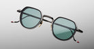 Jacques Marie Mage Dixon sunglasses with hexagonal frames, green lenses, and black arms shown from the front.