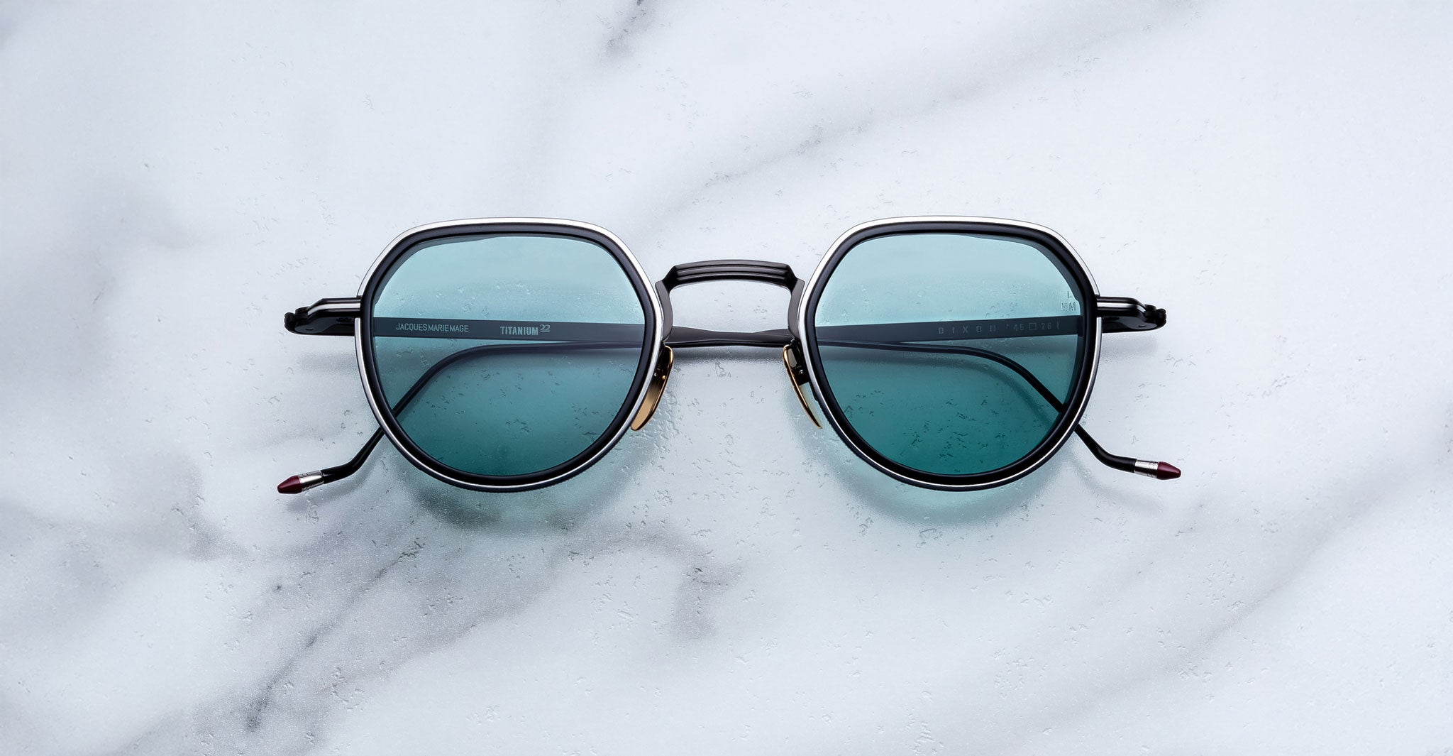 Jacques Marie Mage Dixon sunglasses with blue lenses and black frames, top view.