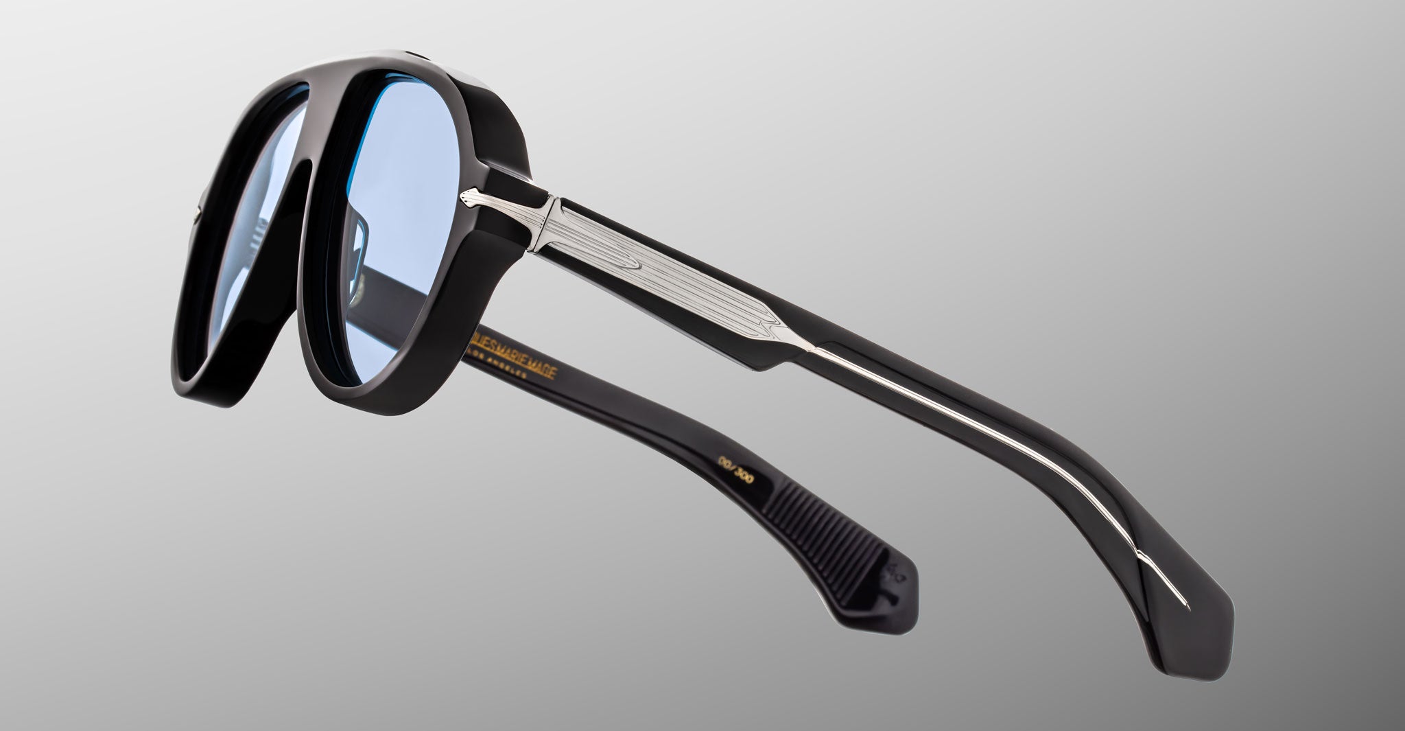 Jacques Marie Mage Donnybrooke in Obscure sunglasses, black frame, blue tinted lenses, metallic accents, profile view.