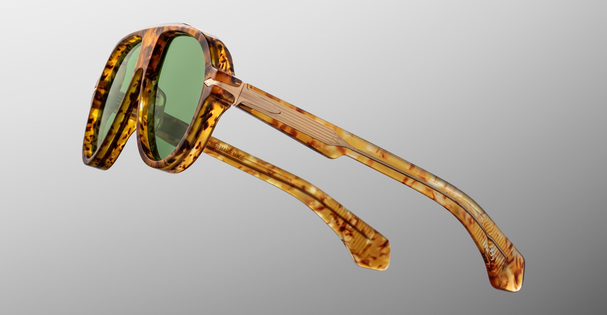 Jacques Marie Mage Donnybrooke oval sunglasses in tortoiseshell with green lenses, displayed against a plain gradient background.
