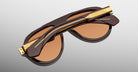 Jacques Marie Mage Donnybrooke in Walnut sunglasses, folded, brown frame with gold accents and UV-protected brown-tinted lenses, back view.