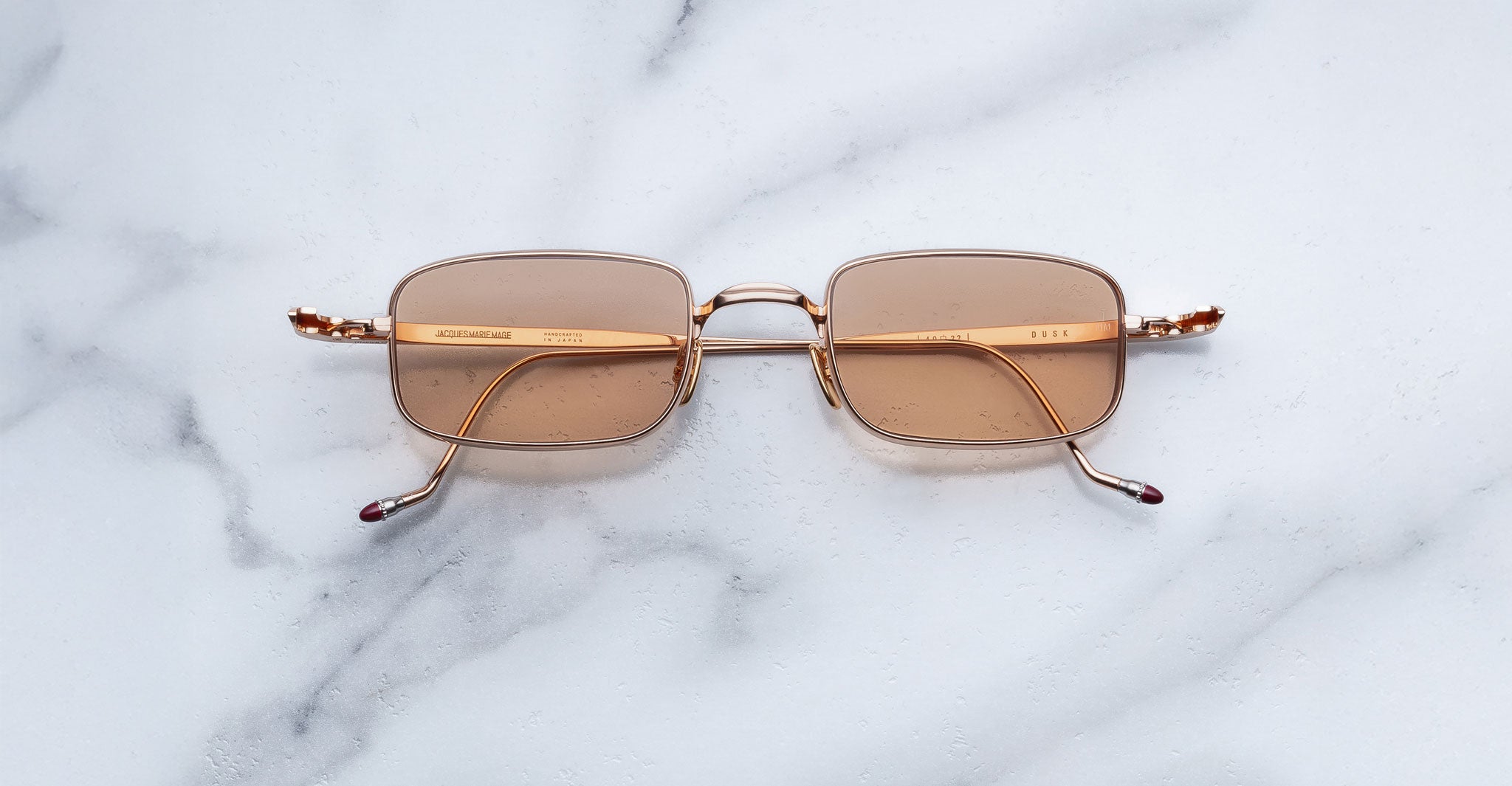 Jacques Marie Mage Dusk sunglasses with gold frames and brown lenses, shown from above.