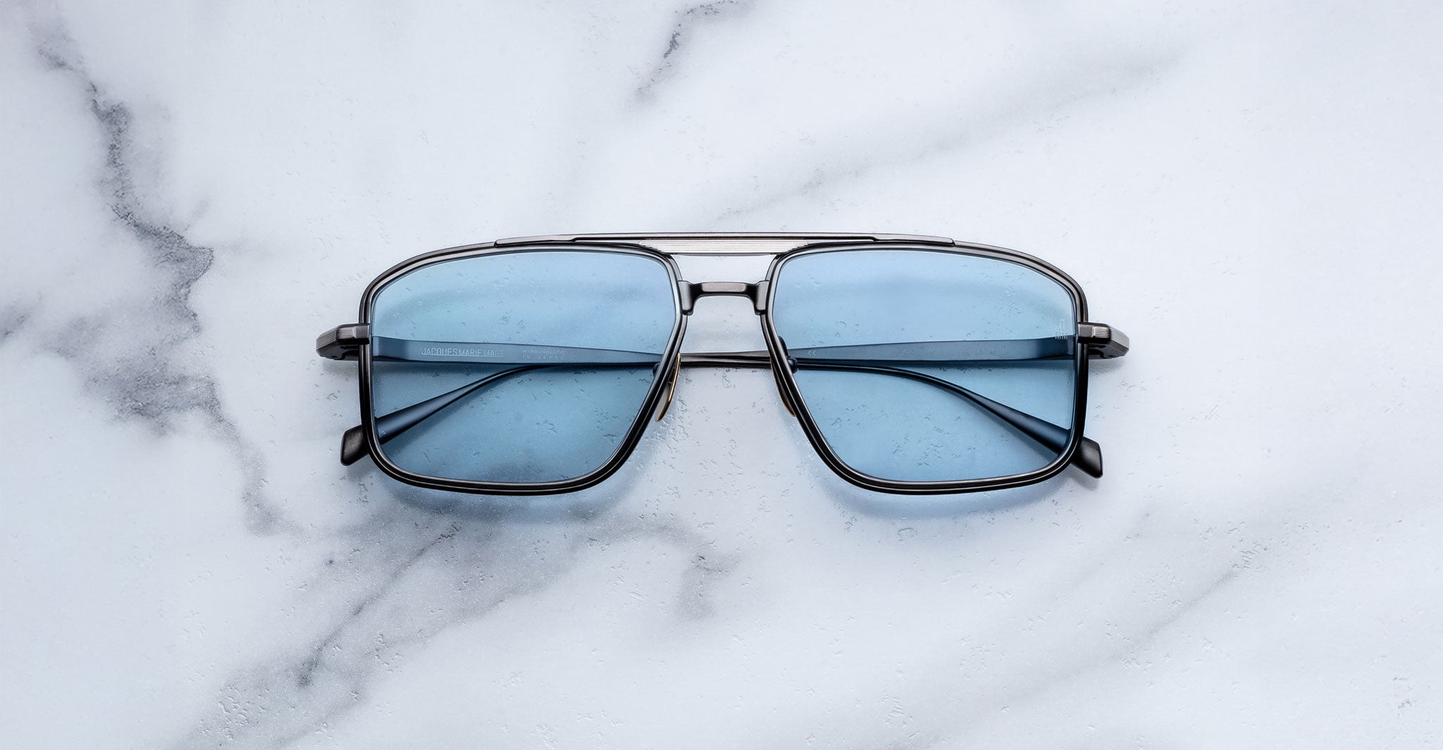Jacques Marie Mage Earl square polarized sunglasses with metal frames and blue-tinted lenses, shown from a front-facing angle.