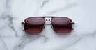 Jacques Marie Mage Earl aviator sunglasses with metal frames and red-tinted lenses shown from above.
