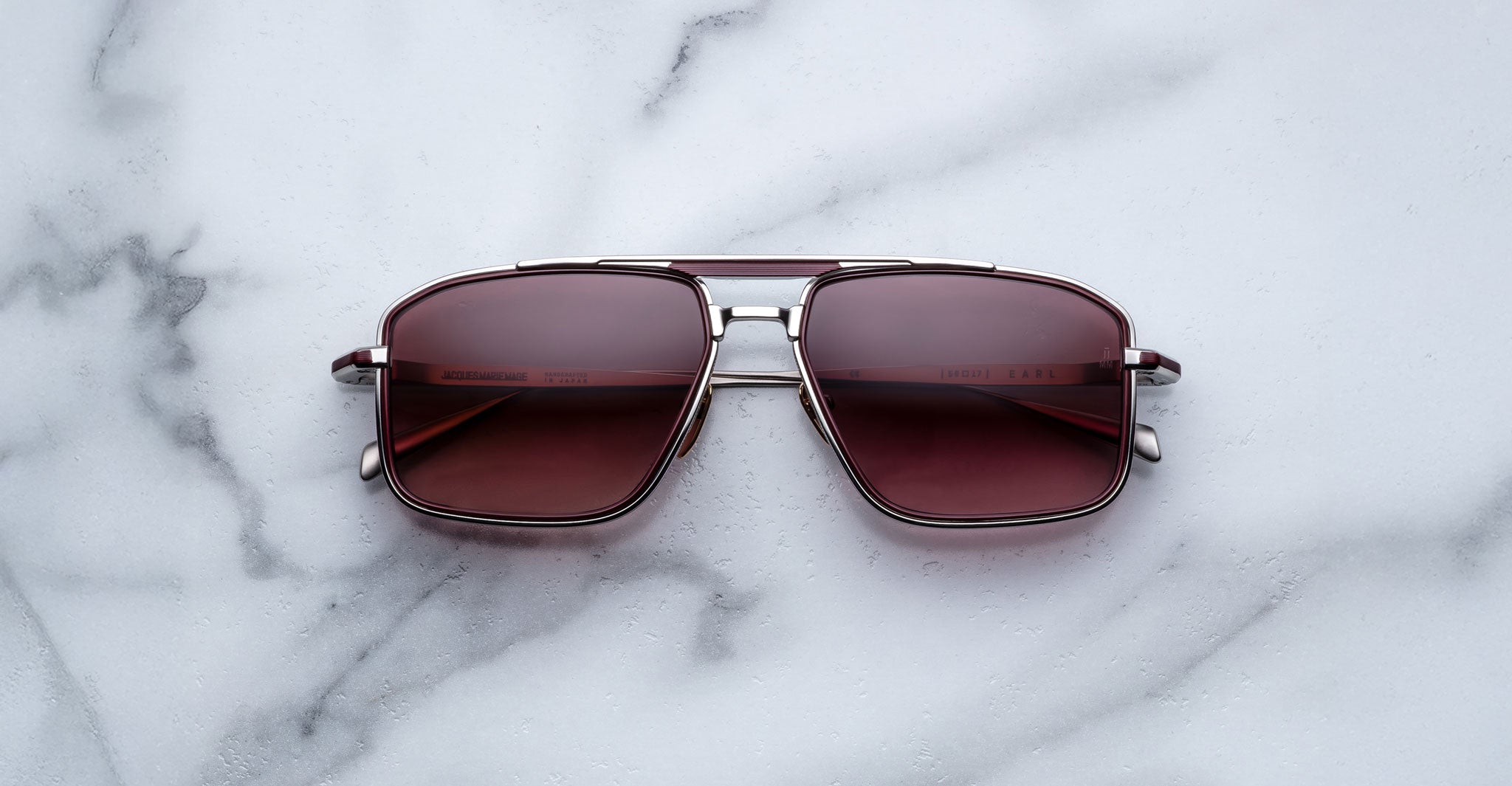Jacques Marie Mage Earl aviator sunglasses with metal frames and red-tinted lenses shown from above.