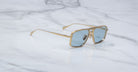 Jacques Marie Mage Earl sunglasses with gold frames and blue-tinted lenses, top view.