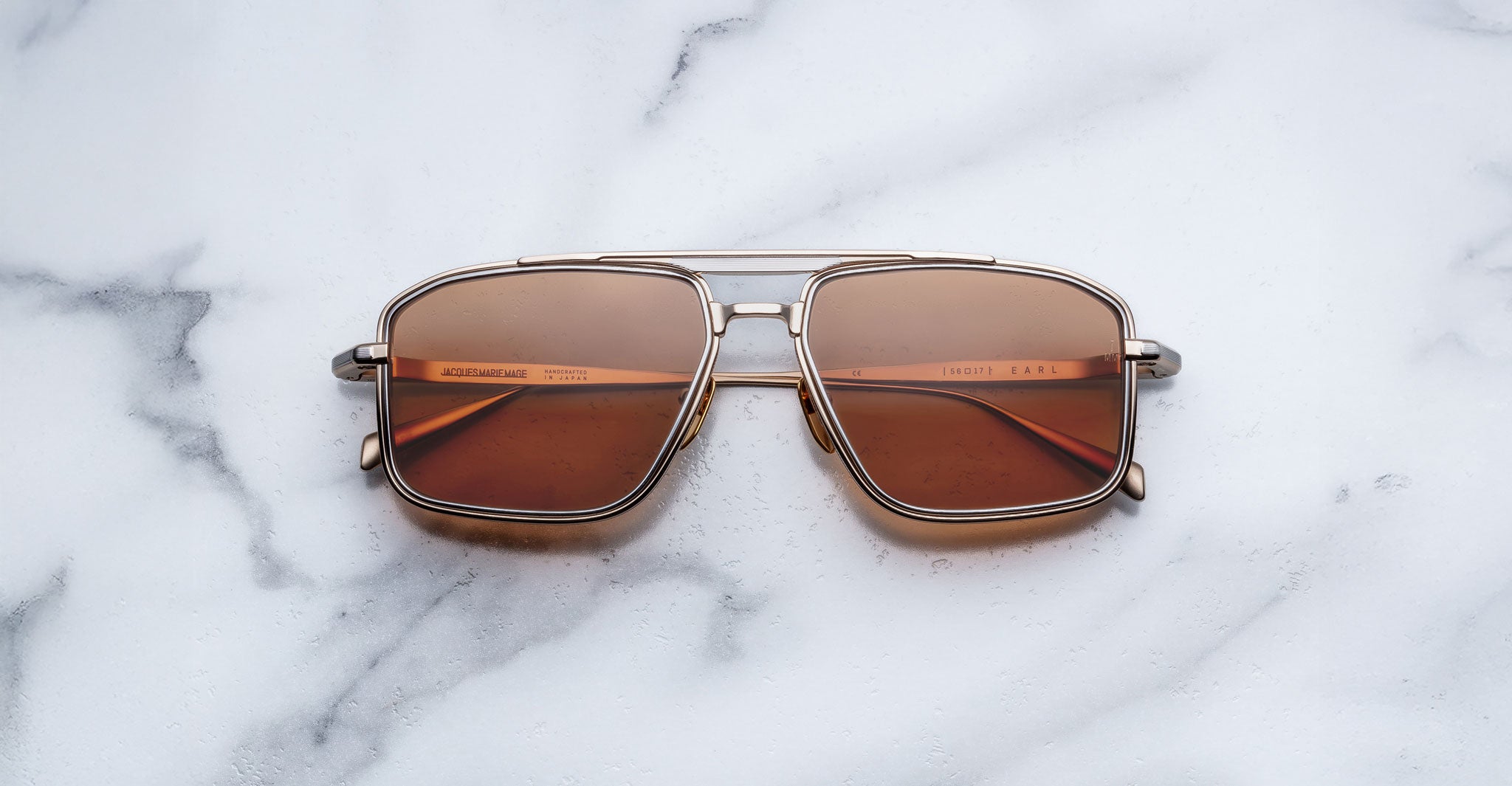 Jacques Marie Mage Earl aviator sunglasses with brown lenses and gold frames, shown from above.