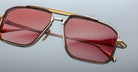Close-up of Jacques Marie Mage Earl gold-framed sunglasses with red rectangular lenses, front view.