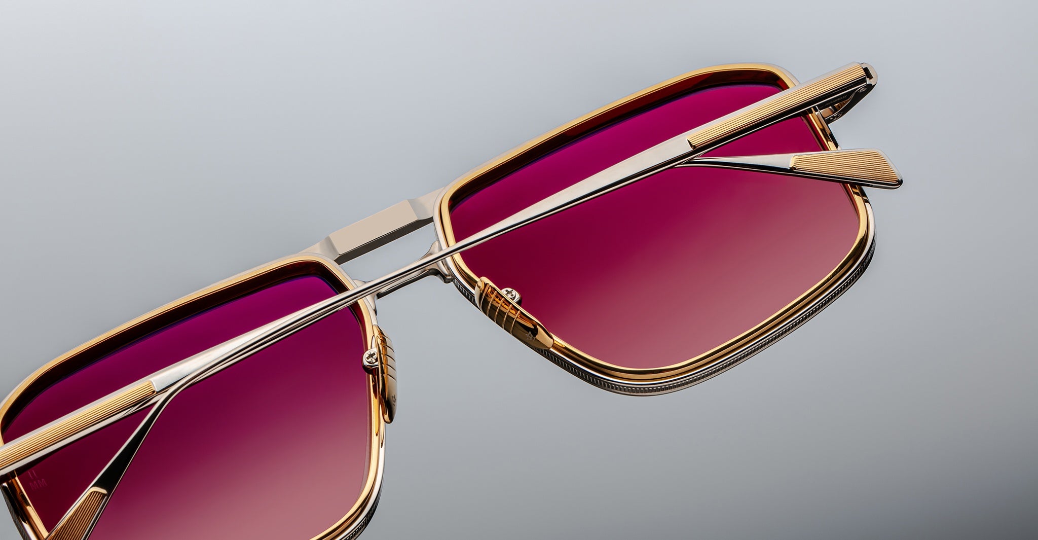 Close-up of Jacques Marie Mage Earl sunglasses, gold frame, rectangular gradient pink lenses, viewed from the front.