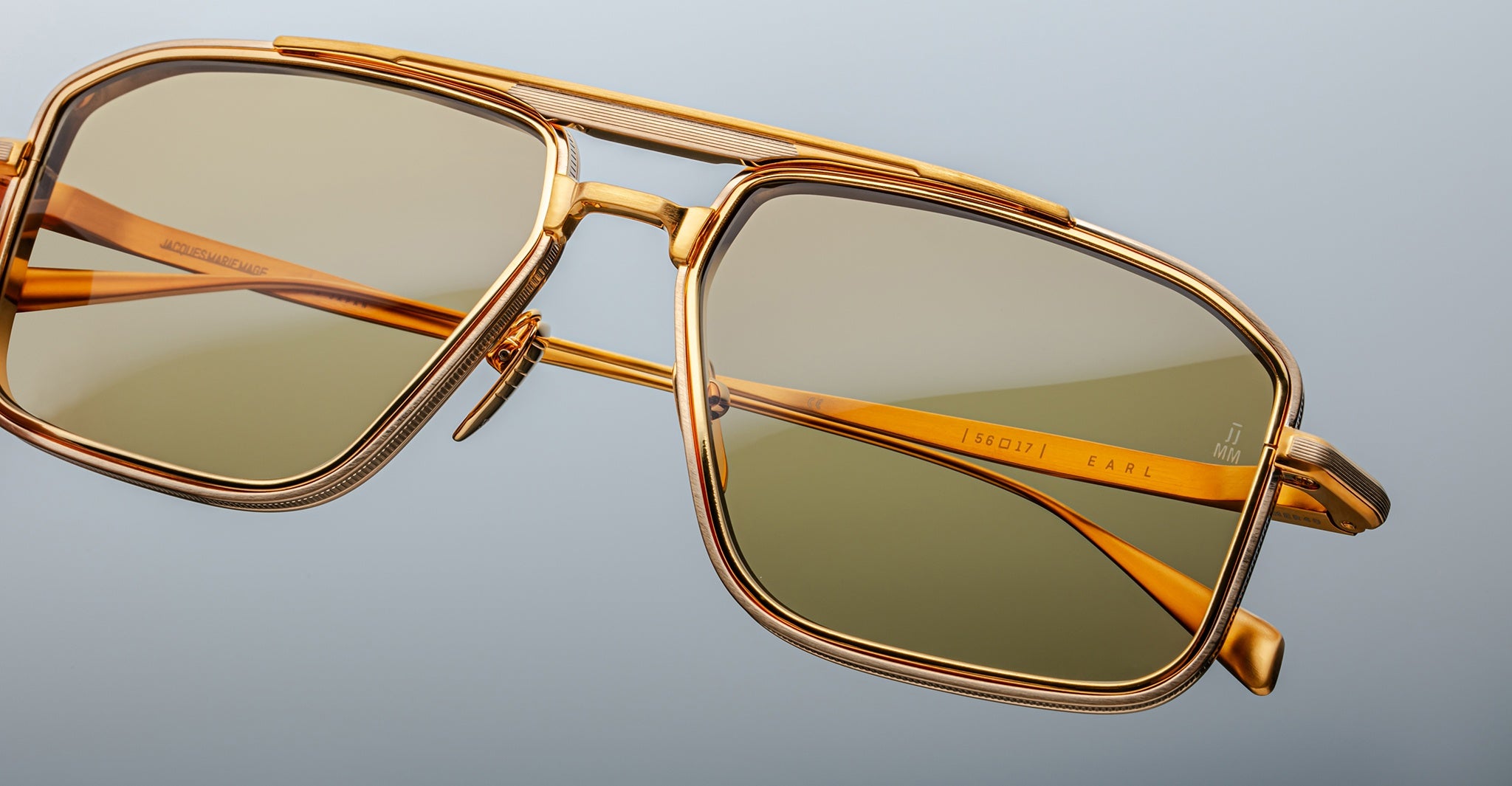 Close-up of Jacques Marie Mage Earl gold aviator sunglasses with green polarized lenses, front angle view.
