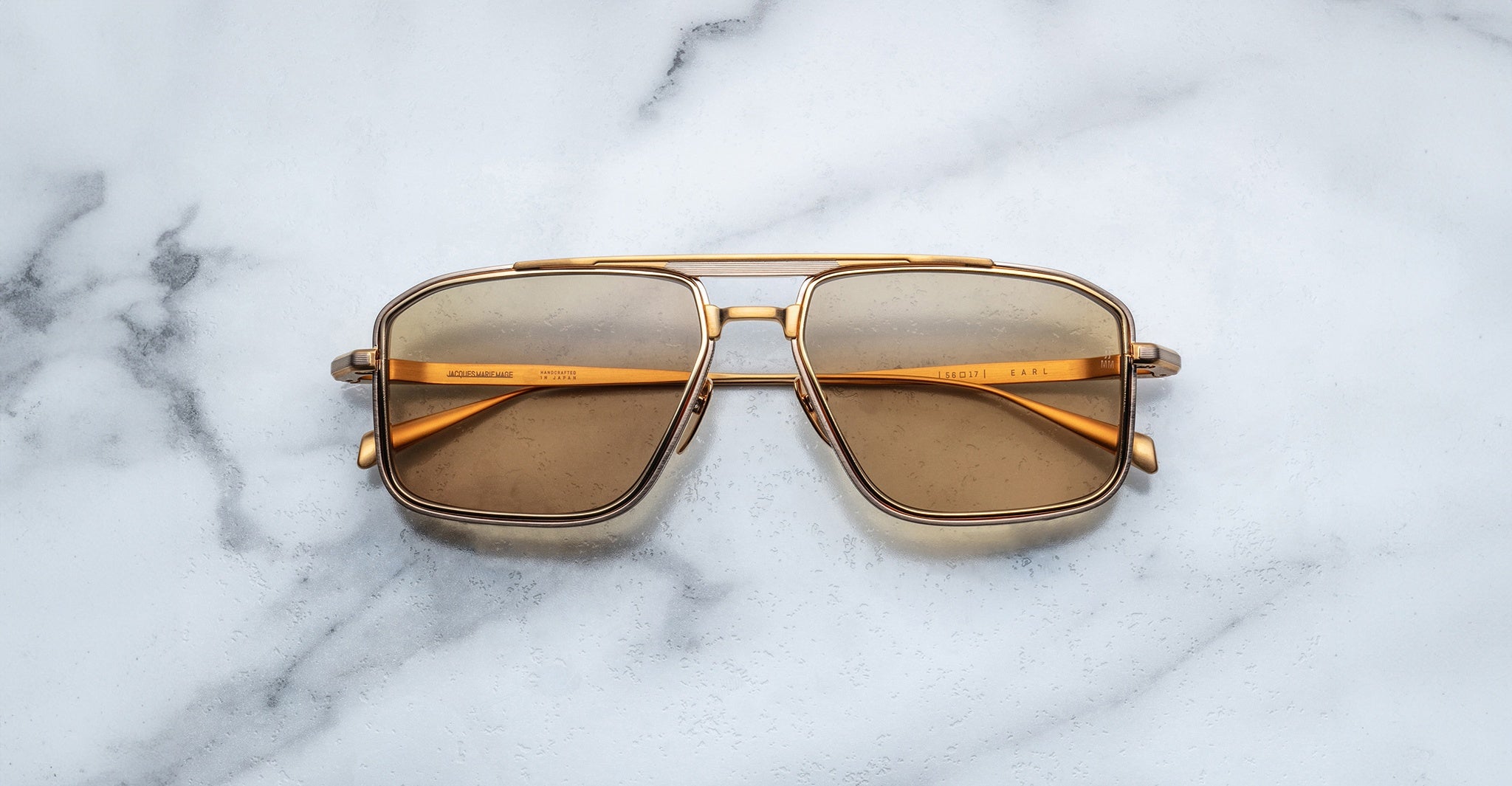 Jacques Marie Mage Earl aviator sunglasses with gold frames and brown lenses, top view.