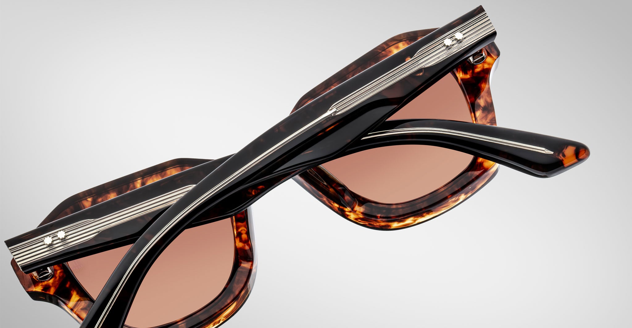 Detailed back view of a pair of Jacques Marie Mage Eichler Havana color, thick-framed sunglasses with brown lenses on a plain background