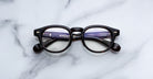 Jacques Marie Mage Eiko round tortoiseshell eyeglasses with crossed arms, viewed from above.