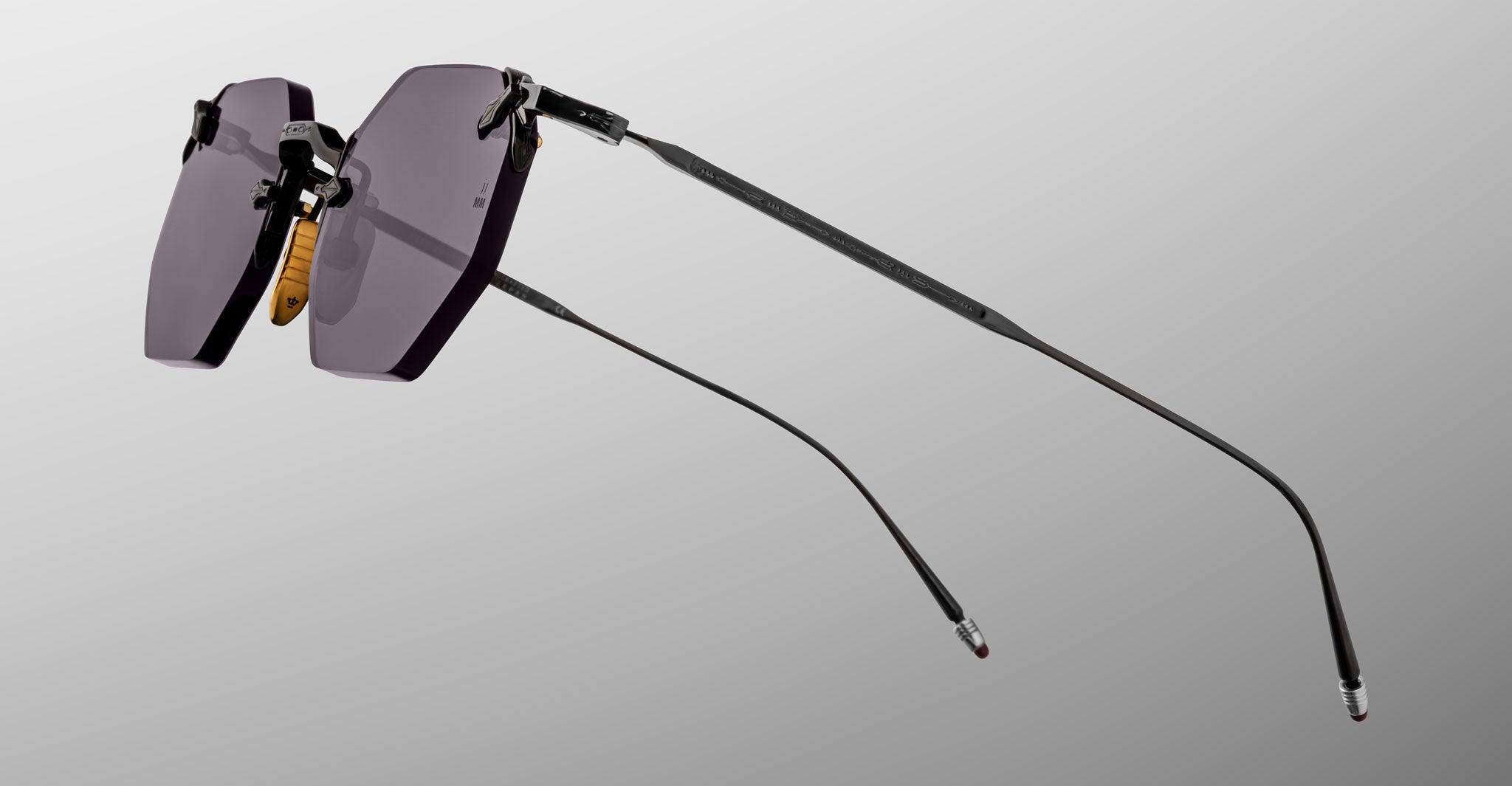 The Jacques Marie Mage El Dorado sunglasses feature a rimless design, dark tinted lenses, thin black metal temples, and nose pads, displayed against a plain gray background.