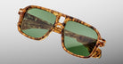 The Jacques Marie Mage Elkhart is a limited-edition oversized navigator sunglass with a brown tortoiseshell frame, sculpted brow ridge, and green lenses, shown against a plain light gray background.