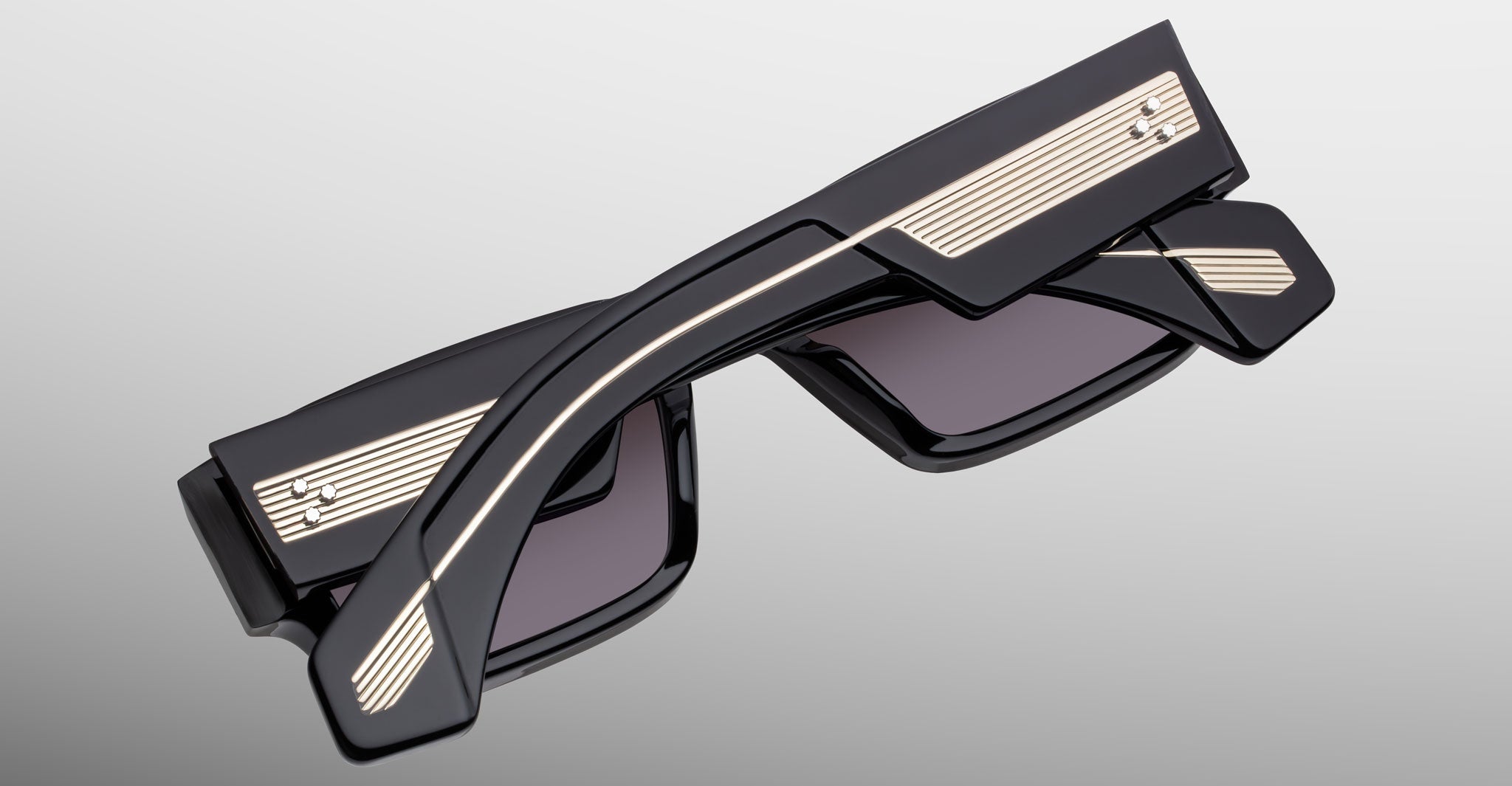 Jacques Marie Mage Engel folded black sunglasses with gold-accented arms, side view.