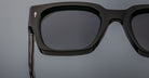 Close-up of left side of Jacques Marie Mage Enzo black square sunglasses with dark UV-protective lenses, side angle.
