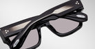 Close-up of Jacques Marie Mage Enzo black rectangular eyeglasses, silver accents, and two white dots on the temples.