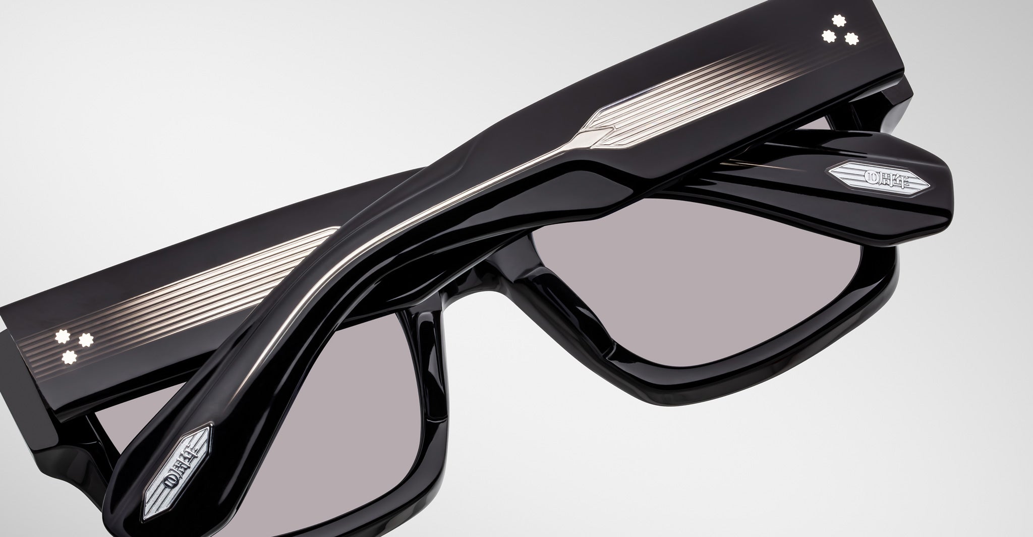 Close-up of Jacques Marie Mage Enzo black rectangular eyeglasses, silver accents, and two white dots on the temples.