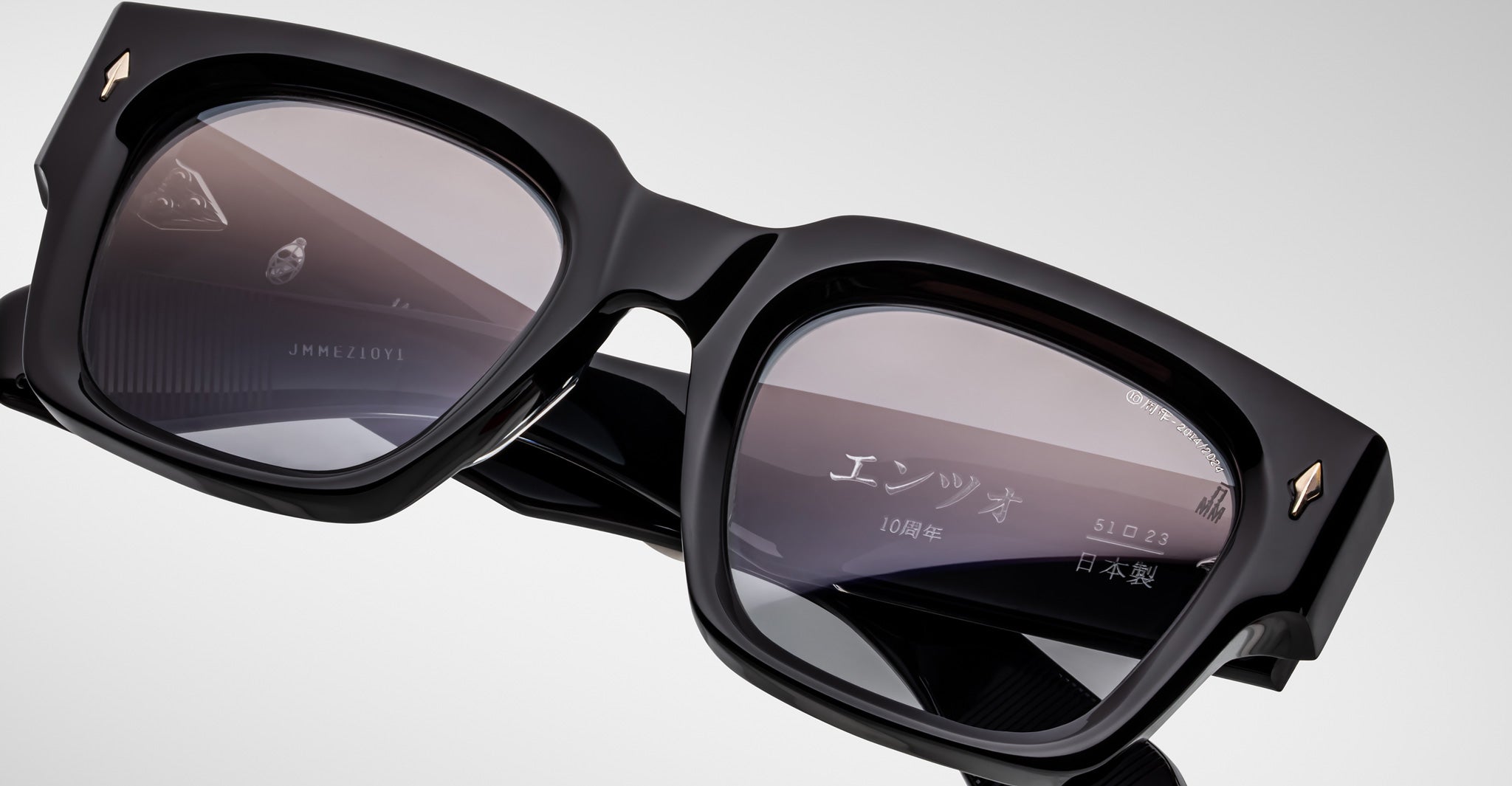 Close-up of Jacques Marie Mage Enzo black rectangular eyeglasses with metal accents and Japanese text on the right lens.