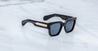 Jacques Marie Mage Enzo sunglasses, black square frame with gold accents and blue UV lenses, front view.
