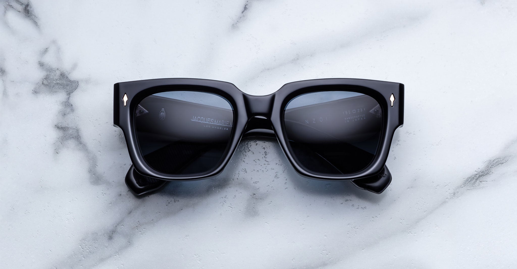 Jacques Marie Mage Enzo black rectangular sunglasses with dark lenses, viewed from above.