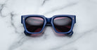 Jacques Marie Mage Enzo blue rectangular sunglasses with dark lenses, viewed from above, display their modern frame design.