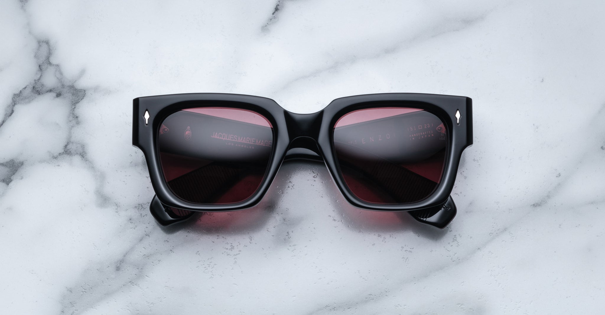 Jacques Marie Mage Enzo black square sunglasses with dark red lenses, viewed from above.