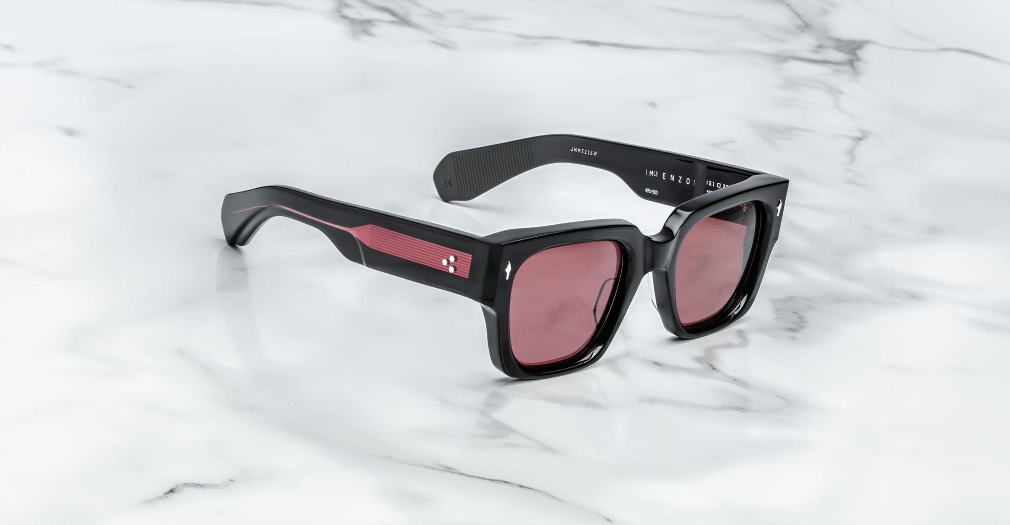 Jacques Marie Mage Enzo sunglasses with thick frames and red-tinted lenses, viewed from above.