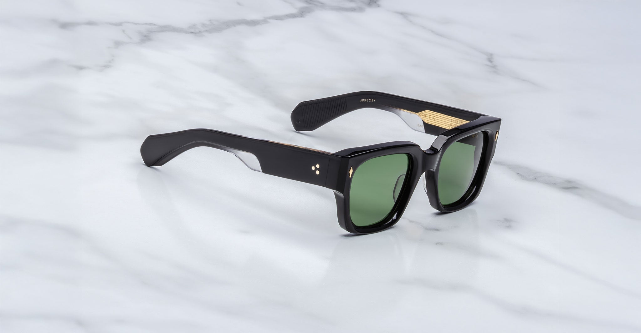Jacques Marie Mage Enzo black rectangular sunglasses with green lenses and gold accents, shown from above.