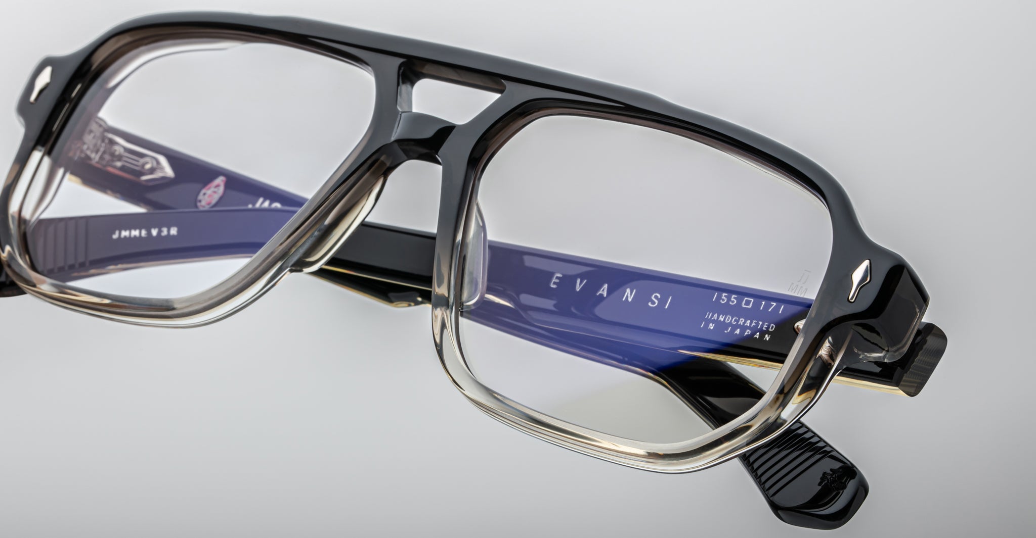 Close-up of Jacques Marie Mage Evans optical glasses with black and clear handcrafted oversized acetate frame and visible branding on the blue inner temple.