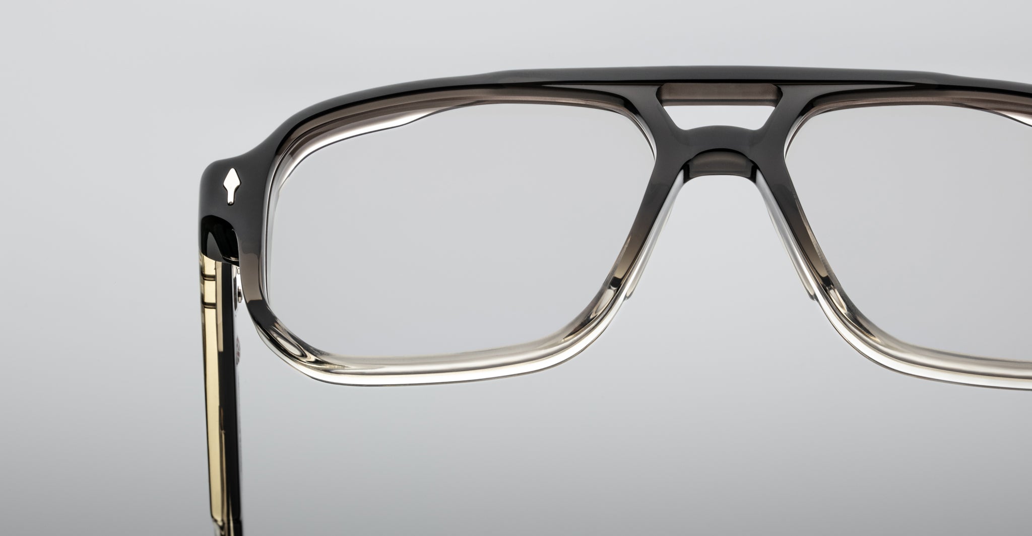 Close-up of the upper half of Jacques Marie Mage Evans optical glasses, showcasing an oversized handcrafted acetate frame against a plain grey background.