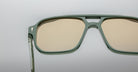 Close-up of Jacques Marie Mage Evans sunglasses with oversized green acetate frames and beige-tinted lenses, set against a plain light gray background.