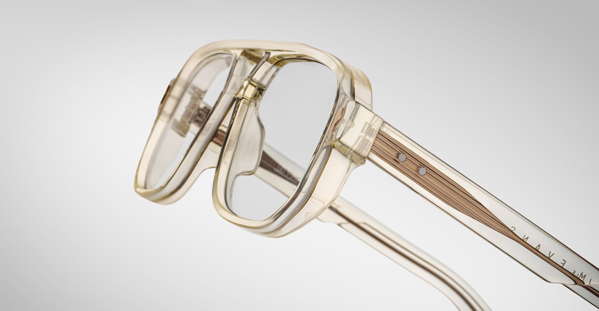 Close-up of Jacques Marie Mage Evans optical glasses, showcasing a thick oversized acetate frame, clear lenses, and metal temple accents against a plain light background.