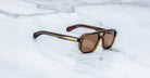 Jacques Marie Mage Evans sunglasses with brown polarized lenses and gold accents shown from above.
