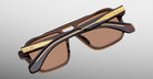 Jacques Marie Mage Evans brown and gold sunglasses, folded, top view. Model and brand name visible.