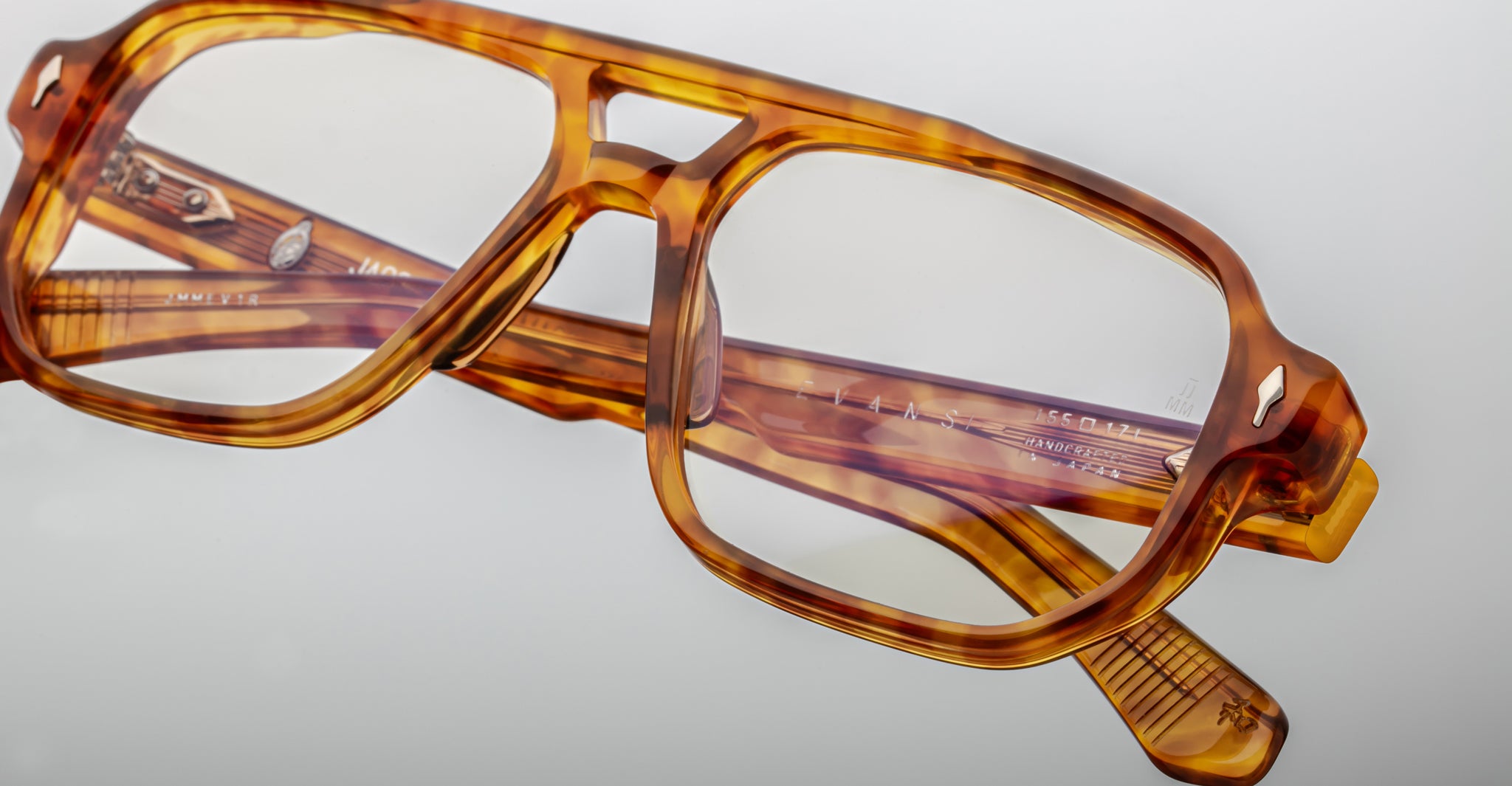 Close-up of Jacques Marie Mage Evans rectangular optical glasses in tortoiseshell, featuring clear lenses and folded neatly on a light gray surface.