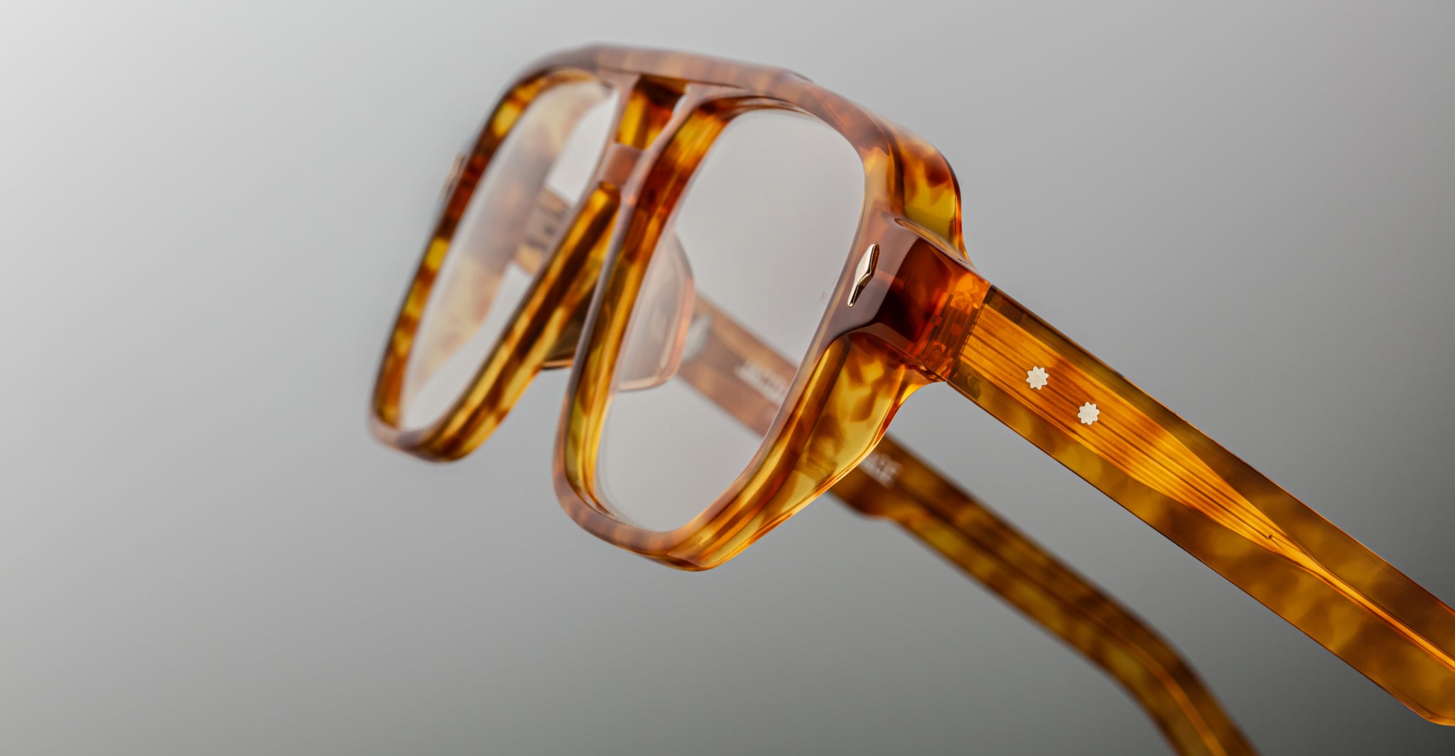 Close-up of Jacques Marie Mage Evans optical glasses showcasing a handcrafted oversized acetate frame in tortoiseshell pattern with two small white star-shaped details on the temple.
